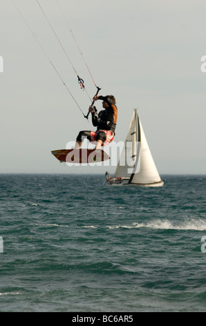 Kitesurfer in der Luft mit Segelyacht im Hintergrund Stockfoto