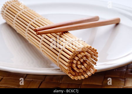 eine horizontale Makro ein paar Stäbchen und ein Sushi Rollen Matte auf einem weißen Teller Stockfoto