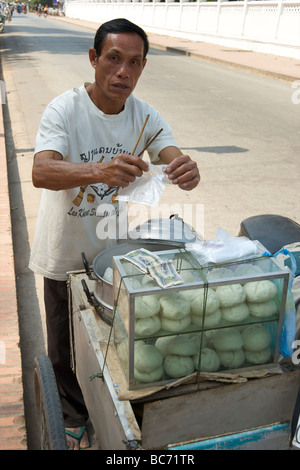 Ein Lao-Mann mit Stäbchen, seine chinesische Knödel aus seiner mobilen Küche in Luang Prabang Laos zu erlegen Stockfoto