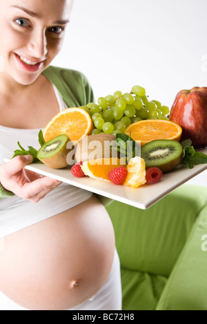 Schwangere Frau mit Obstteller Stockfoto