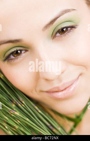 Frau mit grünem Make-up und Pflanze neben dem Gesicht Stockfoto