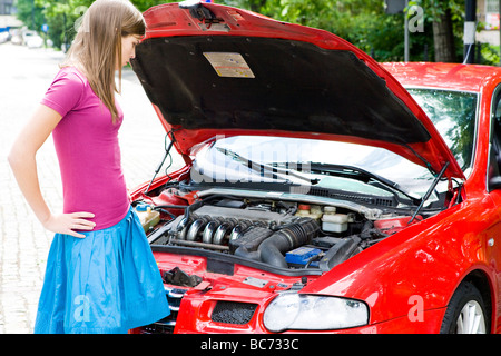 junge Frau, die unter Motorhaube Stockfoto