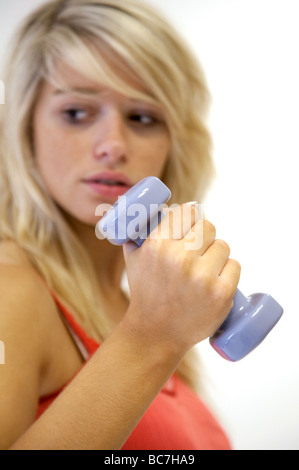 Eine junge Frau, die durch Verwendung von Gewichten im Fitnessstudio, UK Stockfoto