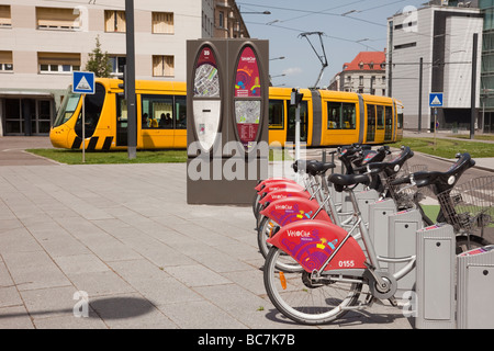 Mulhouse Elsass Frankreich Europa Geschwindigkeit e-Bikes zu vermieten in der Straßenbahnstation mit gelben Tram Zug auf s-Bahn-Netz Stockfoto