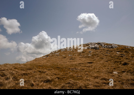 Oben auf dem grasbewachsenen Hügel und Wolken am blauen Himmel Stockfoto