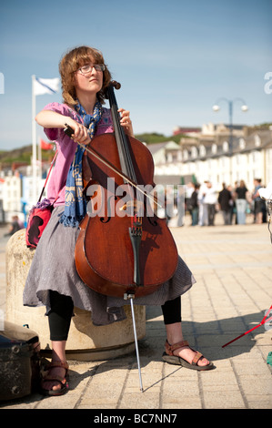 Eine junge Frau Straßenmusiker ihr Cellospiel auf Aberystwyth Promenade an einem sonnigen Sommernachmittag der s Wales UK Stockfoto