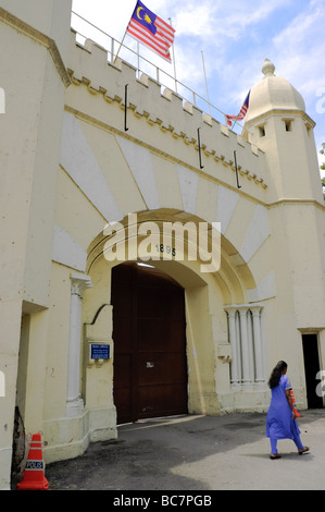 Frau zu Fuß vorbei an der imposanten Gateway eines Gefängnisses. Stockfoto