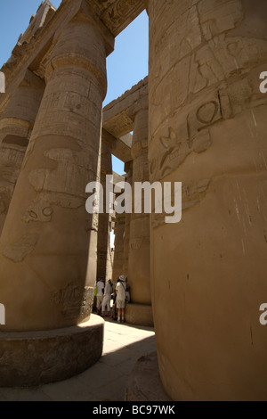 Eine Gruppe von Touristen sind in den Schatten gestellt durch die riesigen Säulen in die große Säulenhalle, Karnak Tempel, Luxor, Ägypten Stockfoto