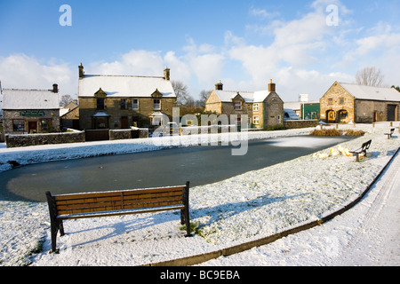 Ein Blick über den Dorfteich von Hartington unter einer Decke von Schnee im Peak District in Derbyshire Stockfoto