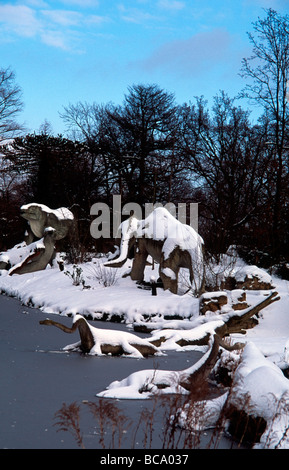 Viktorianischen Modelle der Gruppe der Dinosaurier im Schnee rund um Crystal Palace Park Lake South London England Stockfoto