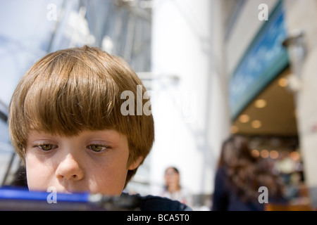 Nahaufnahme von sieben Jahre alter Junge Videospiel Nintendo ds auf einem Flughafen Stockfoto