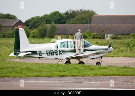 Grumman American AA-5 Traveller G-BBSA mit Crew verlassen Flugzeugs in Sandtoft Flugplatz geparkt. Stockfoto