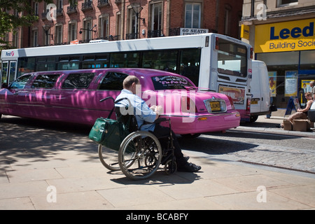 Ein Mann in einem Rollstuhl, eine rosa Limousine und einen Bus in Sheffield City Centre Stockfoto