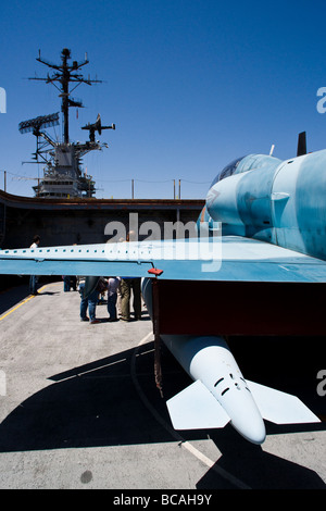 Ein a-4 Skyhawk, gemalt in einem Aggressor Farbe Muster senkt sich nach vorne Flugzeug Aufzug auf USS Hornet. Stockfoto