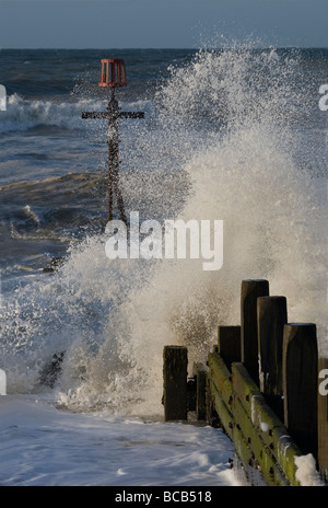 Brechenden Wellen gegen die Buhnen, Norfolk Küste. Stockfoto