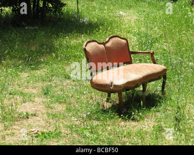 eine alte beschädigte Sofa in Feld auf Land entsorgt Stockfoto