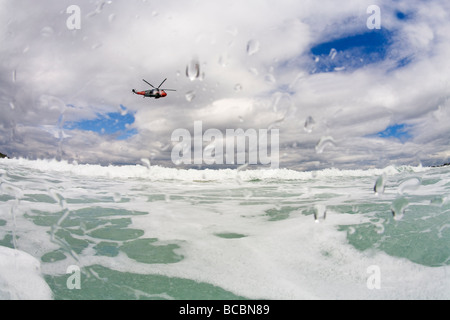 Royal Navy Such- und Rettungshubschrauber überfliegt Wellen vor Porthmeor Beach im Sommer St Ives Cornwall England UK GB Stockfoto