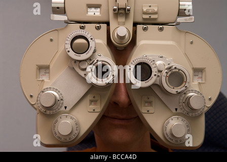 Mann mit Auge am Phoropter Head Ausrüstung, Farnham, Surrey, UK mit Optiker testen. Stockfoto