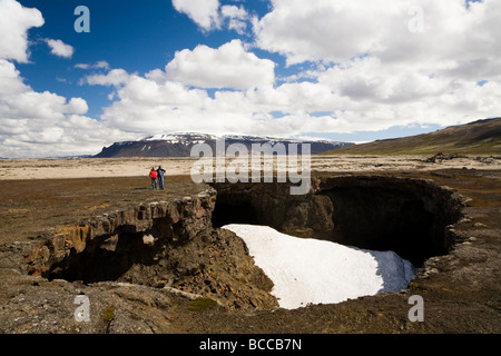 Mutter und Tochter stehen neben einer Höhle Öffnung.  Die Höhle Surtshellir, Lavafeld Hallmundarhraun, Westisland. Stockfoto