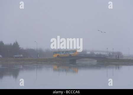 Menschen, die über eine Brücke über Tjörnin-Sees bei einem regnerischen nebeligen Tag Downtown Reykjavik Island Stockfoto