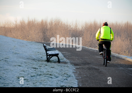 Radfahrer fahren Fahrrad auf Schnee bedeckt Straße in Herrington Country Park, Sunderland, England. Stockfoto