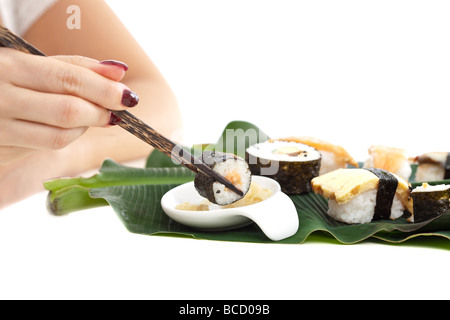 Frau Hand hält eine Sushi-Rolle mit Stäbchen Stockfoto