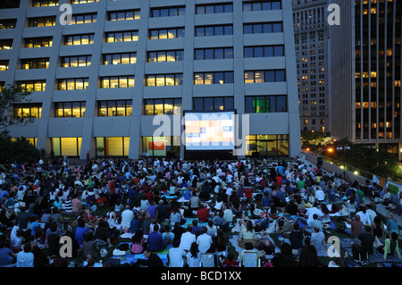 Umgeben von Bürogebäuden in Manhattans Financial District, sammelt eine Menge in einem kleinen Park, einen Outdoor-Film zu sehen. Stockfoto