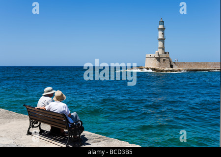 Paar, sitzen auf einer Bank vor dem Leuchtturm, alten venezianischen Hafen, Chania, Nordwestküste, Kreta, Griechenland Stockfoto