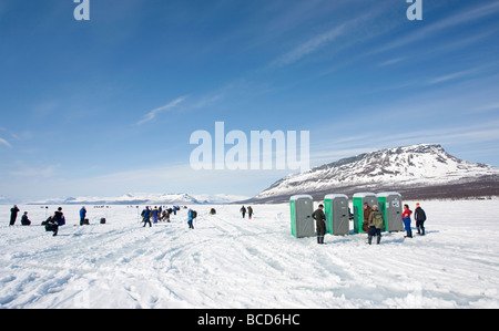 Menschen, die Schlange um arktische Toilettenhäuschen am See Kilpisjärvi Eis während einer Eis-Angelwettbewerb Saana Fjell, Finnland Stockfoto