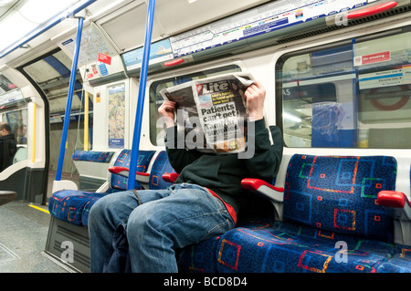 Mann liest Kopie der Gratiszeitung London Lite auf einer u-Bahn England Großbritannien UK Stockfoto