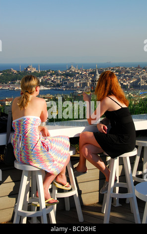 ISTANBUL, TÜRKEI. Zwei junge Frauen trinken & Mikla in Richtung Sultanahmet von Bar auf der Dachterrasse betrachten. 2009. Stockfoto