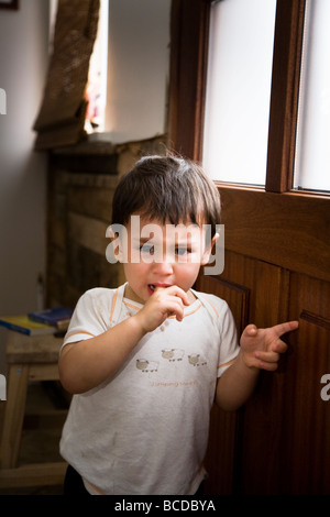 Kleiner Junge wartet an der Tür zu Hause, für seine Mutter weint. Stockfoto