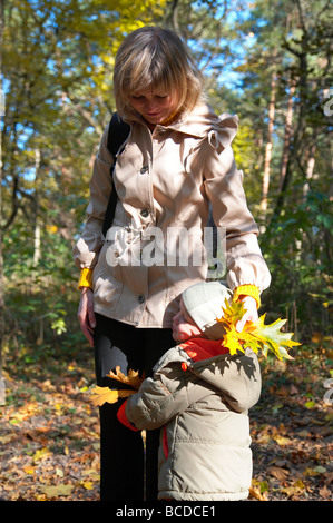 Glückliche Familie (Mutter mit kleinen Jungen) im goldenen Herbst Stadtpark Stockfoto