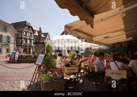 Menschen im Straßencafé auf dem Place du Chateau Square in mittelalterliches Dorf an der Weinstraße. Eguisheim-Haut-Rhin-Elsass-Frankreich. Stockfoto