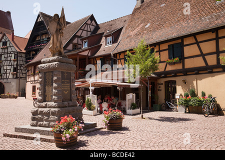 Kriegerdenkmal und Fachwerkbauten in mittelalterlichen Dorfplatz an der Weinstraße. Eguisheim Elsass Frankreich. Stockfoto