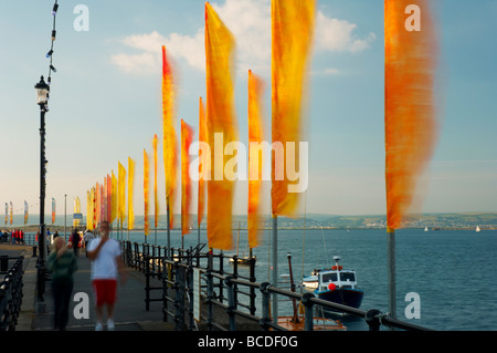 Massen von Menschen zu Fuß Vergangenheit farbigen hell Fahnen flattern im Wind am Strand von Appledore North Devon UK Stockfoto