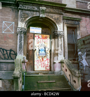 Eine Tür mit Graffiti an einem verlassenen Brownstone-Haus in einem Harlem Viertel New York City, NY, in dem die USA untergebracht sind KATHY DEWITT Stockfoto