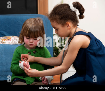 Mädchen, die Ärzte spielen, und Patienten, die Bandagen anziehen Stockfoto