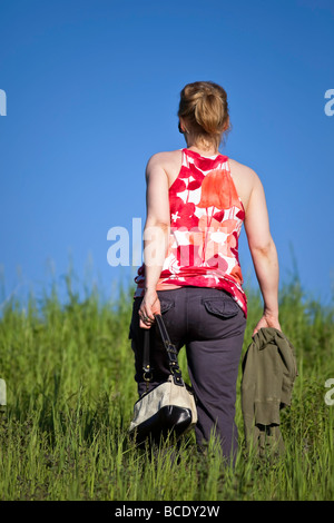 Rückansicht der Frau, die im hohen Gras, Manitoba, Kanada, spazieren geht. Stockfoto
