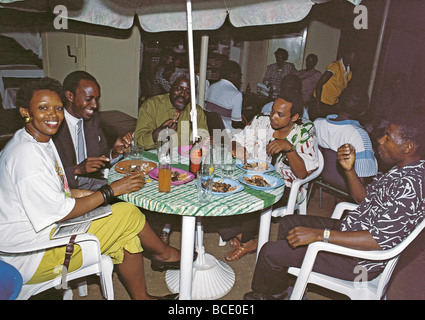 Gemischte Gruppe von jungen afrikanischen Männern und Frauen genießen Nyama Choma Braten am Straßencafé Kampala-Uganda-Ost-Afrika Stockfoto