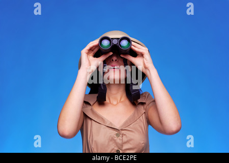 Eine Frau trägt ein Tropenhelm mit ein paar Ferngläser blauen Hintergrund mit Textfreiraum suchen Stockfoto