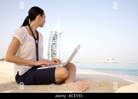 Frau sitzt am Strand auf laptop Stockfoto