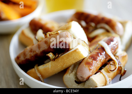 Frisch gekochte Wurst aus Schweinefleisch Hot Dogs mit Zwiebeln in einem weißen Brot Crusty Roll serviert in einer Schüssel mit Keine Personen Stockfoto