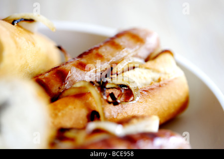 Frisch gekochte Wurst aus Schweinefleisch Hot Dogs mit Zwiebeln in einem weißen Brot Crusty Roll serviert in einer Schüssel mit Keine Personen Stockfoto