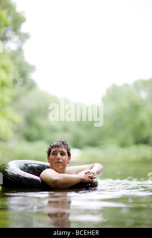 Teenager sitzen alleine im Wasser in einem innertube Stockfoto