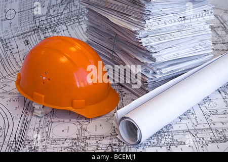 Gelbe, rote Aktenordner, Helm und Haufen von Konstruktionszeichnungen liegen auf dem Tisch. Unternehmen Still-Leben. Stockfoto