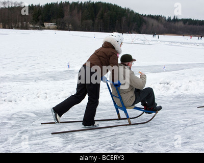 Älteres Ehepaar mit einem Kick-Schlitten an einem See in Schweden Stockfoto