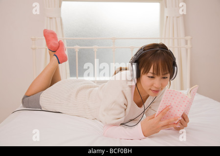 Junge Frau Buch auf Bett Stockfoto