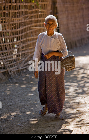 Myanmar, Burma, Mrauk U. Eine alte Rakhine geht eine schmale Straße in der Nähe von ihrem Haus am Stadtrand von Mrauk U. Stockfoto