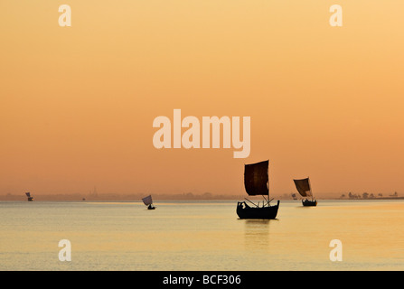 Myanmar, Burma, Rakhine-Staat Kaladan Fluss. Einen goldenen Sonnenuntergang am Fluss Kaladan als Segelboote Leiter für Zuhause. Stockfoto